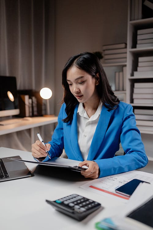 Young woman in a blue suit reviewing reports.